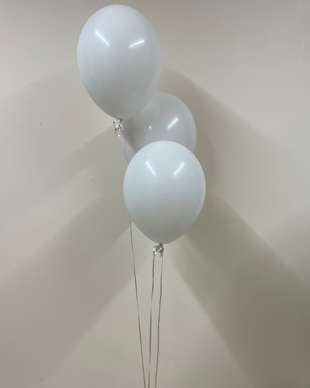 Three white balloons against a plain background