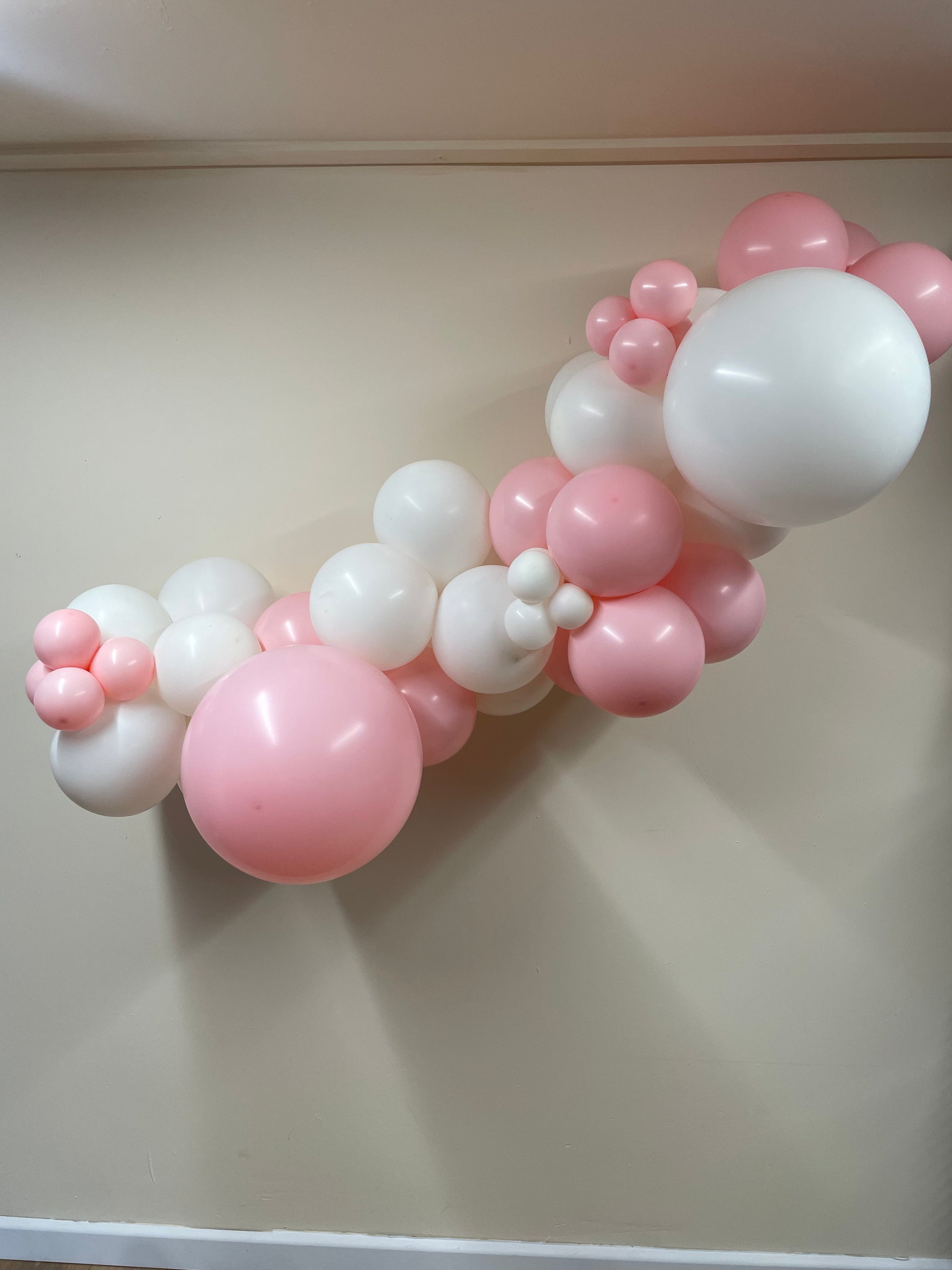 Balloon arch with pink and white balloons on a plain background