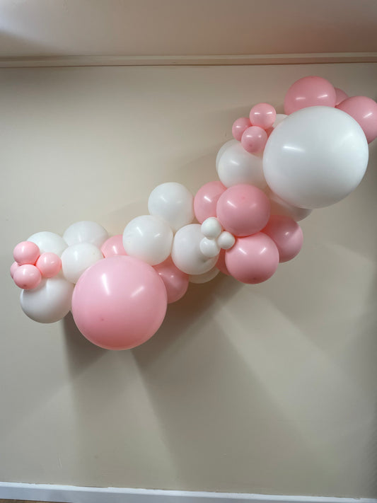 Balloon arch with pink and white balloons on a plain background