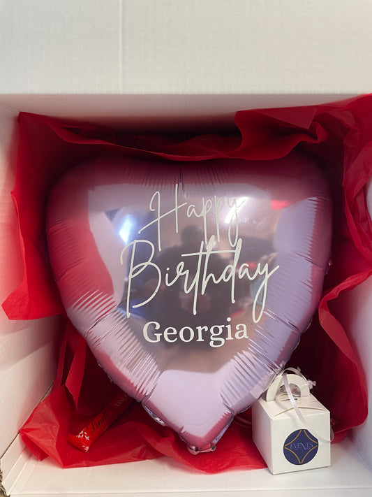 Heart-shaped birthday balloon with 'Happy Birthday Georgia' text in a box with red tissue paper.
